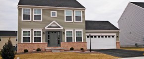 Exterior of house with siding and brick, large garage, driveway, lawn and sidewalk
