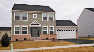 Exterior of house with siding and brick, large garage, driveway, lawn and sidewalk