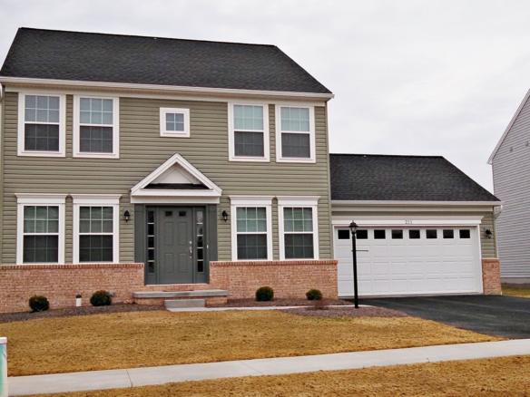 Exterior of house with siding and brick, large garage, driveway, lawn and sidewalk