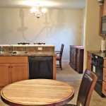 Kitchen with small table, black appliances, wood cabinets, and brown marble-style countertops