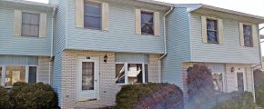 Exterior of townhouse with yellow brick and blue siding with yellow shutters