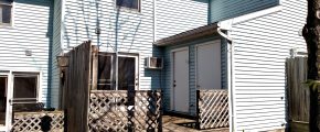 Exterior of townhouse with blue siding and wooden deck off the back of the house