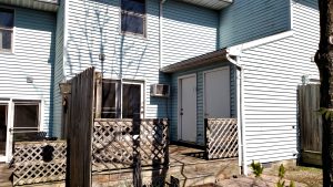 Exterior of townhouse with blue siding and wooden deck off the back of the house