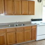 Kitchen with wood-tone cabinets, double bowl sink and white appliances