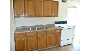 Kitchen with wood-tone cabinets, double bowl sink and white appliances