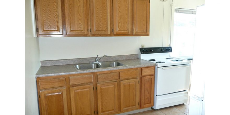 Kitchen with wood-tone cabinets, double bowl sink and white appliances