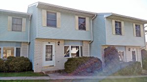 Exterior of townhouse with yellow brick and blue siding with yellow shutters