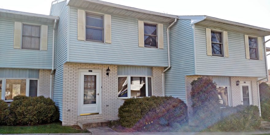 Exterior of townhouse with yellow brick and blue siding with yellow shutters