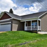 House with gray siding, a white garage, a driveway, and grassy front lawn
