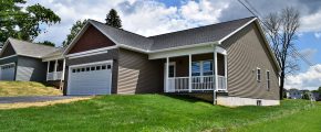 House with gray siding, a white garage, a driveway, and grassy front lawn