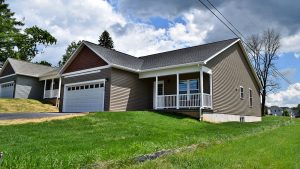 House with gray siding, a white garage, a driveway, and grassy front lawn