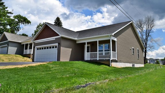 House with gray siding, a white garage, a driveway, and grassy front lawn