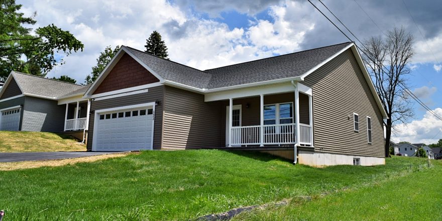 House with gray siding, a white garage, a driveway, and grassy front lawn