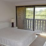 Bedroom with large queen bed and large sliding glass door that opens to balcony