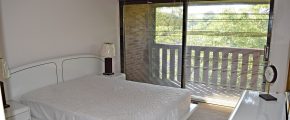 Bedroom with large queen bed and large sliding glass door that opens to balcony