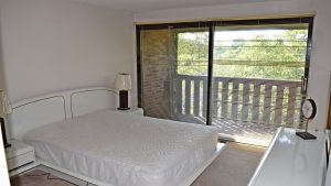 Bedroom with large queen bed and large sliding glass door that opens to balcony