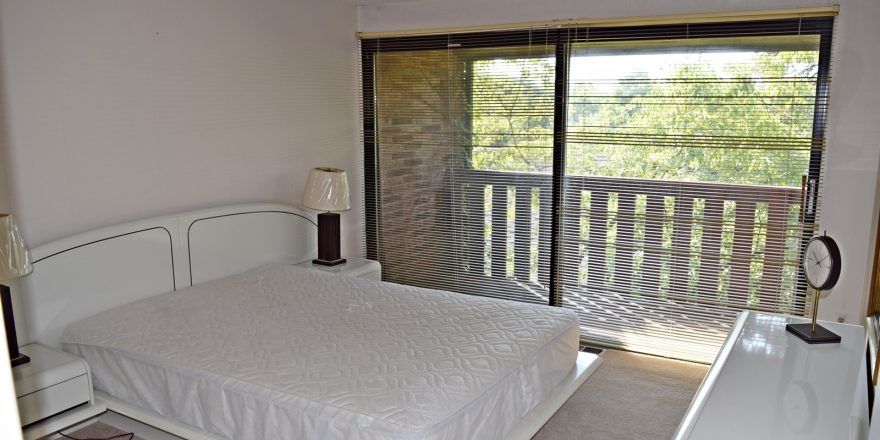 Bedroom with large queen bed and large sliding glass door that opens to balcony