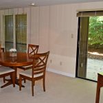 Dining room with oval table and four chairs, large mirrored wall and large sliding glass door onto a patio