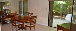 Dining room with oval table and four chairs, large mirrored wall and large sliding glass door onto a patio