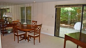 Dining room with oval table and four chairs, large mirrored wall and large sliding glass door onto a patio