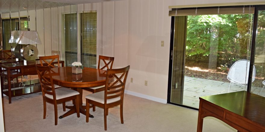 Dining room with oval table and four chairs, large mirrored wall and large sliding glass door onto a patio