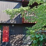 Exterior of a townhome with a bright red front door and brown large-panel siding