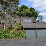 Exterior of a townhome with ivy on the fence and three large garages