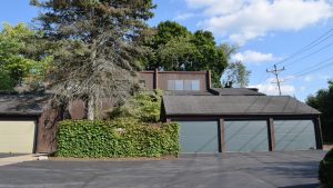 Exterior of a townhome with ivy on the fence and three large garages