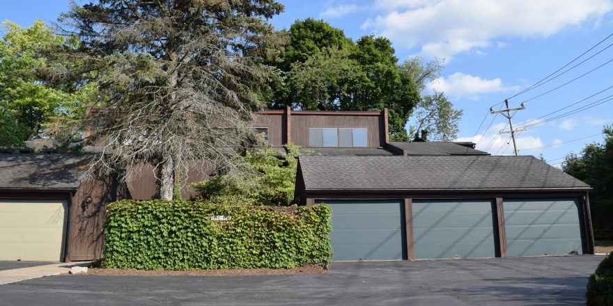 Exterior of a townhome with ivy on the fence and three large garages