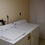 Laundry room with side-by-side top load washer and front load dryer and a closet