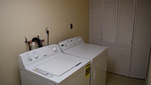 Laundry room with side-by-side top load washer and front load dryer and a closet