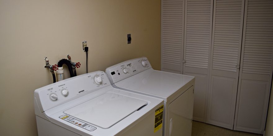 Laundry room with side-by-side top load washer and front load dryer and a closet