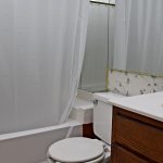 Bathroom with floral wallpaper, shower/tub combo, toilet, and vanity.