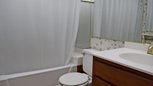 Bathroom with floral wallpaper, shower/tub combo, toilet, and vanity.