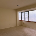 Unfurnished, carpeted bedroom with large windows