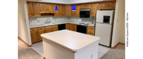 Kitchen with white and black appliances, tile flooring, wood cabinets, and large island