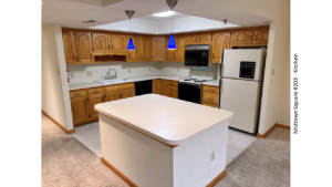 Kitchen with white and black appliances, tile flooring, wood cabinets, and large island