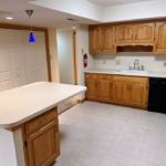 Kitchen with white and black appliances, tile flooring, wood cabinets, and large island