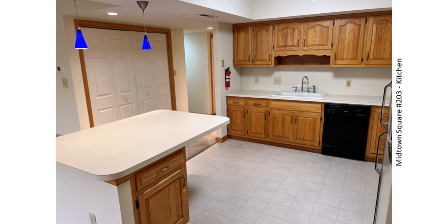 Kitchen with white and black appliances, tile flooring, wood cabinets, and large island