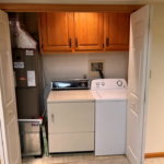 Laundry closet with side-by-side front load washer and top load dryer with cabinets