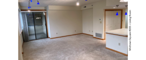 Carpeted living room with arm chair, tv stand, and large windows