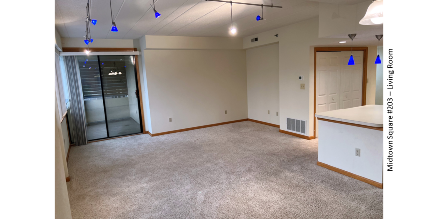 Carpeted living room with arm chair, tv stand, and large windows