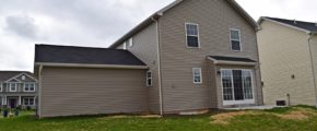 Exterior of house with tan siding, sliding glass door and back yard