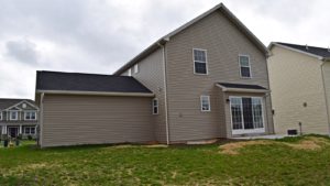 Exterior of house with tan siding, sliding glass door and back yard