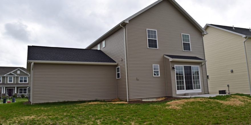 Exterior of house with tan siding, sliding glass door and back yard
