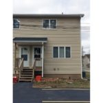 Exterior of duplex with tan siding and covered front entry