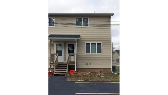 Exterior of duplex with tan siding and covered front entry