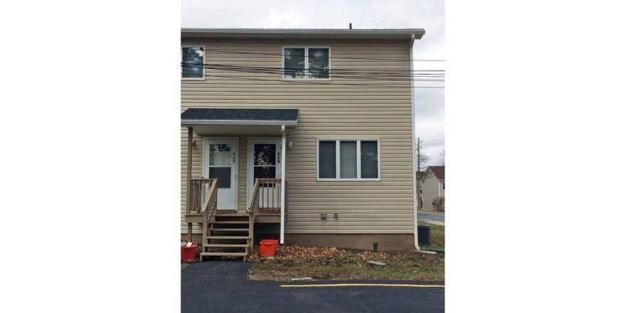 Exterior of duplex with tan siding and covered front entry