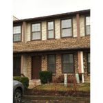 Exterior of townhouse with brick first floor, and yellow siding on the second floor
