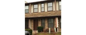 Exterior of townhouse with brick first floor, and yellow siding on the second floor